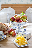 Freshly baked bread and bowl of apples on a laid table with porcelain crockery