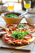 Pizza with fresh rocket and tomato slices served on a wooden board