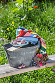 Zinc tub in the summer garden with bath balls, colourful cloth and bouquet of flowers