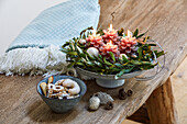 Adventsgesteck mit Kerzen und Gebäck auf Holztisch
