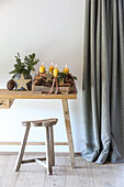 Wooden table with Advent decorations and candles, rustic stool