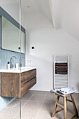 Modern bathroom with suspended wooden washbasin and blue tiles