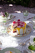 Cake with flower decoration and yellow icing on a garden table in spring