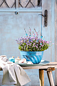 Guglhupf mould with forget-me-nots, tea towel and meringue on a wooden bench in the garden