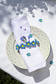 Tablecloth and cloth napkin embroidered with flowers, dotted plate, crocheted flower napkin ring and forget-me-nots