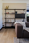 Modernes Wohnzimmer mit schwarzem Metallregal und braunem Sofa
