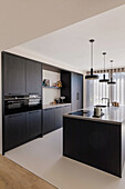 Modern black kitchen with cooking island and hanging lamps
