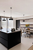 Modern kitchen with black cooking island and dining area with sunflowers and striped wallpaper