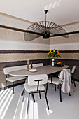 Modern dining area with oval table, sunflowers and striped wallpaper in earthy tones