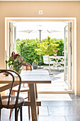 Open patio doors to sunny outdoor area with garden furniture