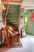Sitting area under the stairs with leo-look armchairs, mint green walls