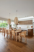 Dining area with wooden table and rattan chairs, modern pendant lights