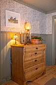 Wooden chest of drawers with candlestick and table lamp in the hallway