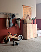 Wooden balance bike and wellies in hallway with wooden cupboard and school map