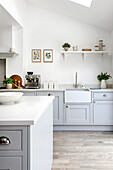 Bright kitchen with farmhouse sink, coffee machine and decor on wall shelf