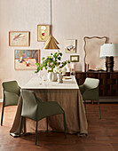 Dining room with linen tablecloth, modern chairs and wall artwork