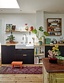 Kitchen with black cupboards, indoor plants and oriental carpet