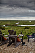 Wooden chairs and fireplace on a gravelled terrace with a view of the wide landscape