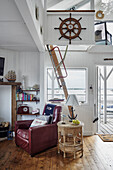 Sailor flair in the living room with red leather armchair, rattan table and wooden steering wheel