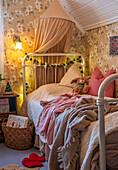 Gemütliches Kinderzimmer mit Metallbett, Baldachin und floraler Tapete