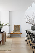 Open-plan living room with wooden table, bar stools and natural decorations