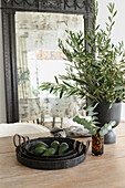 Olive and eucalyptus branches in vases on wooden table, antique mirror