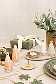 Ceramic decorations with Christmas trees, stars and eucalyptus bouquet on table