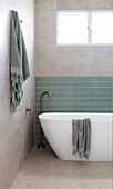 Modern bathroom with free-standing bathtub and green tiled accent wall