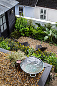 Small gravel garden with seating area and modern bird bath