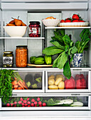 View into a well-stocked fridge with fresh vegetables and pickled delicacies