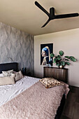Schlafzimmer mit Kunstwerk, Sideboard und Deckenventilator