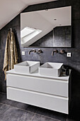 Modern bathroom with double washbasin, dark grey tiles and skylight