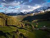 Frühling im Valmüstair / Graubünden im Abendlicht. Lärchen im Austrieb , Bergspitzen noch Schnee bedeckt.