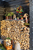 Outdoor woodpile with winter decorations made from fir branches and berry wreaths