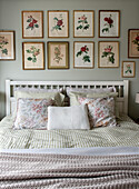 Double bed with chequered bed linen and botanical illustrations on a mint green wall