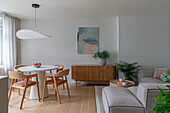 Bright living room with round dining table and Scandinavian wooden furniture