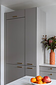 Grey fitted kitchen with golden handles and bouquet of flowers in modern vase