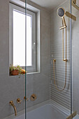 Bathtub with golden fittings, decoration on the window sill