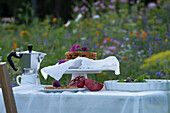 Breakfast table in colourful flower meadow with waffles and coffee