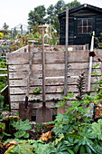 Wooden compost bins and garden tools in the autumn garden
