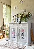 White chest of drawers with colourful mosaic stickers surrounded by boho accessories