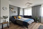 Ausgezogenes Bettsofa, Laminatboden in Holzoptik und moderne Deckenlampe im Wohnzimmer
