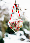 Homemade heart-shaped ice cream pendant with barberry berries and fir branches