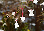Homemade ice cream pendants made from cookie cutters hanging from a bush