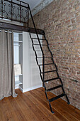 Metal ladder to the open gallery with brick wall