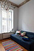 Blue sofa with colourful cushions and striped carpet in an elegant old room