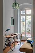 Work area with wooden desk and antique base frame in front of large window front