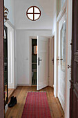 Narrow hallway with wooden floorboards and round skylight