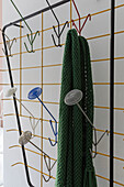 Stylish coat rack made of colourful metal with green scarf