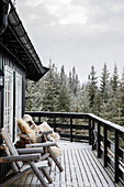 Wooden terrace with rustic seating and views of snow-covered pine trees